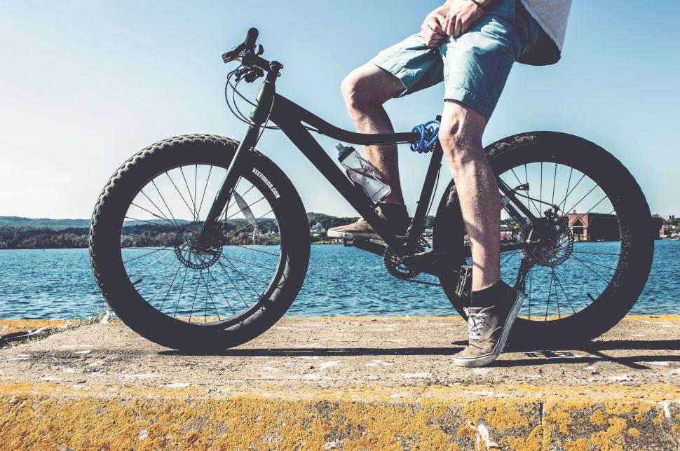 Free Image of Man Riding Bike Alongside Body of Water 