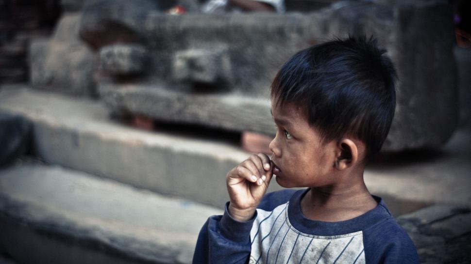 Free Image of Young Boy Standing in Front of Pile of Rubble 