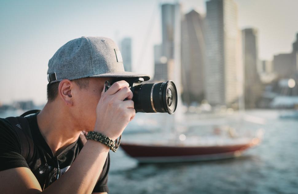 Free Image of Man Taking a Picture of a Boat in the Water 