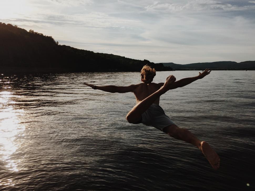 Free Image of Man Jumping Into Water on Surfboard 