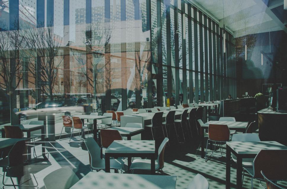 Free Image of Restaurant Interior With Tables, Chairs, and Large Window 