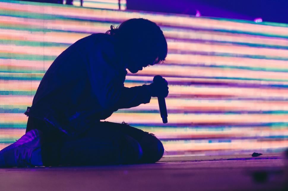 Free Image of Man Sitting on Ground Holding Microphone 