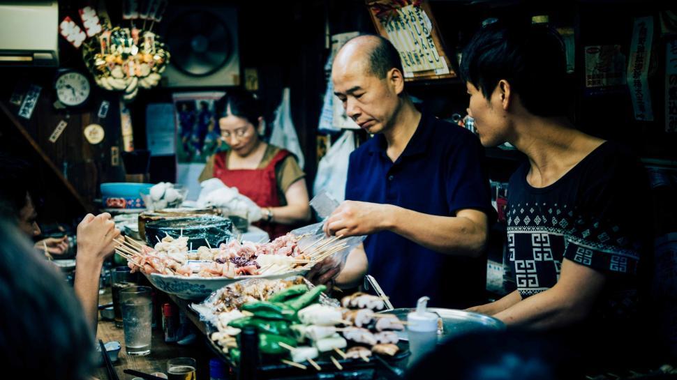 Free Image of Group of People Standing Around Table Filled With Food 