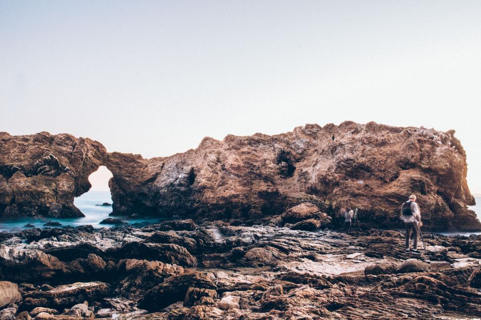 Free Image of Man Standing on Rocky Beach by Ocean 