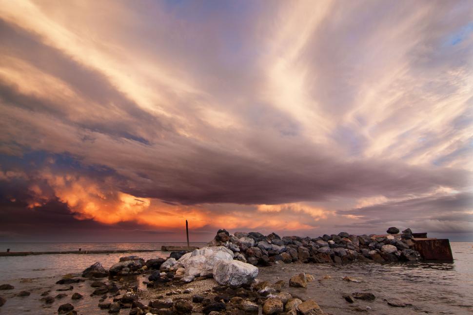Free Image of Cloudy Sky Over Body of Water With Rocks 