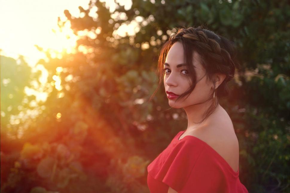 Free Image of Woman in Red Dress Standing in Front of Trees 