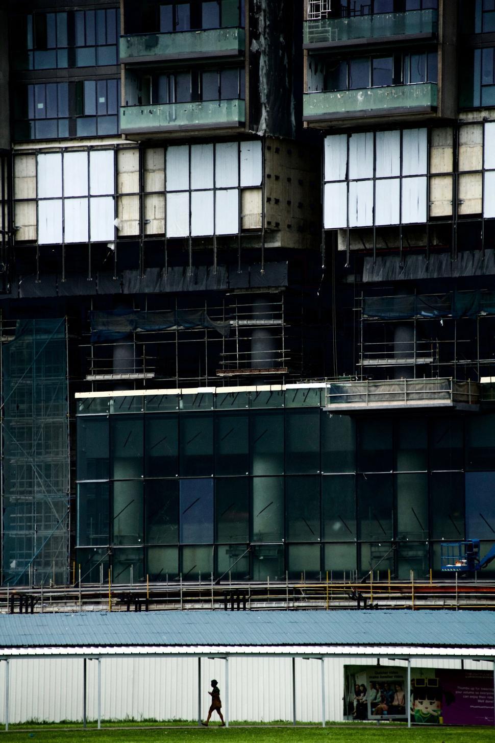 Free Image of Person Walking in Front of Tall Building 