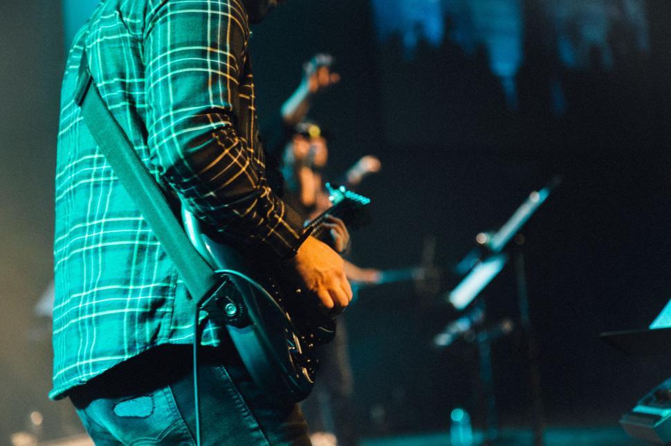 Free Image of Man Standing on Stage Holding Guitar 