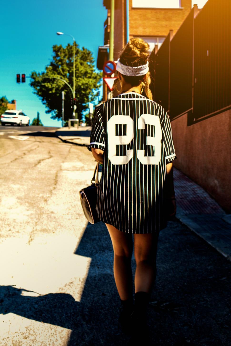 Free Image of Woman Walking Down Street With Hat 