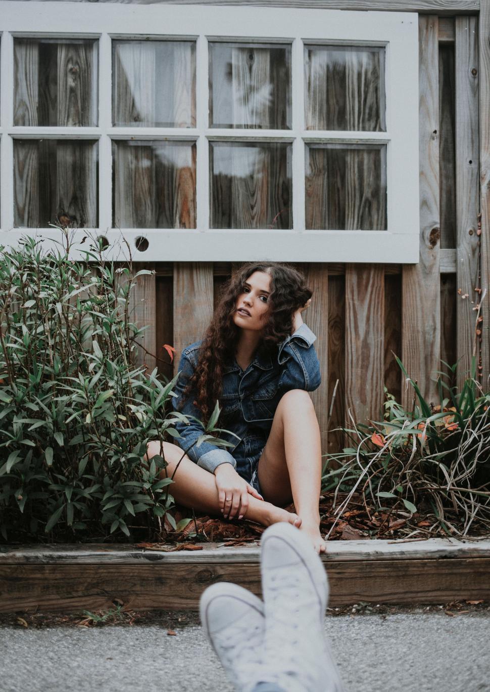 Free Image of Woman Sitting on Ground in Front of House 