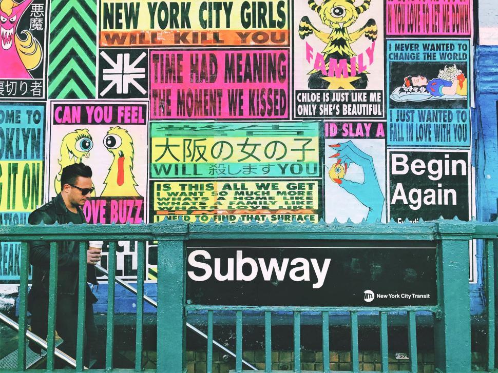 Free Image of Man Sitting on Bench in Front of Wall Covered in Posters 