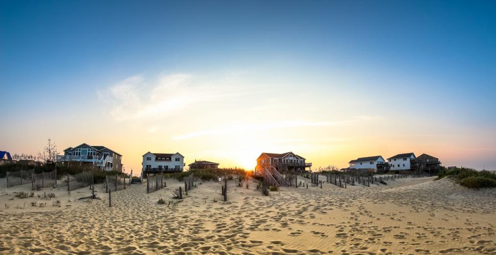 Free Image of Sandy Beach With Houses in Distance 