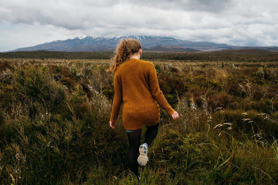 Free Image of Woman Walking Through a Lush Green Field 