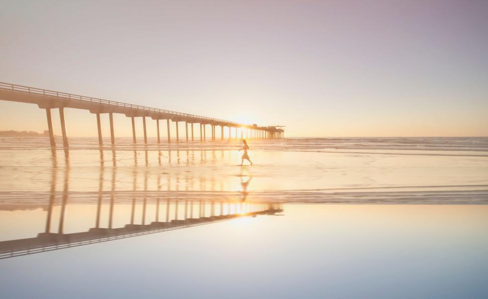 Free Image of Person Walking on Beach Next to Pier 