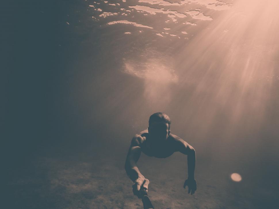 Free Image of Man Dives Into Water to Catch Frisbee 