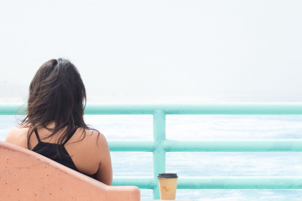 Free Image of Woman Sitting on Bench by Ocean 
