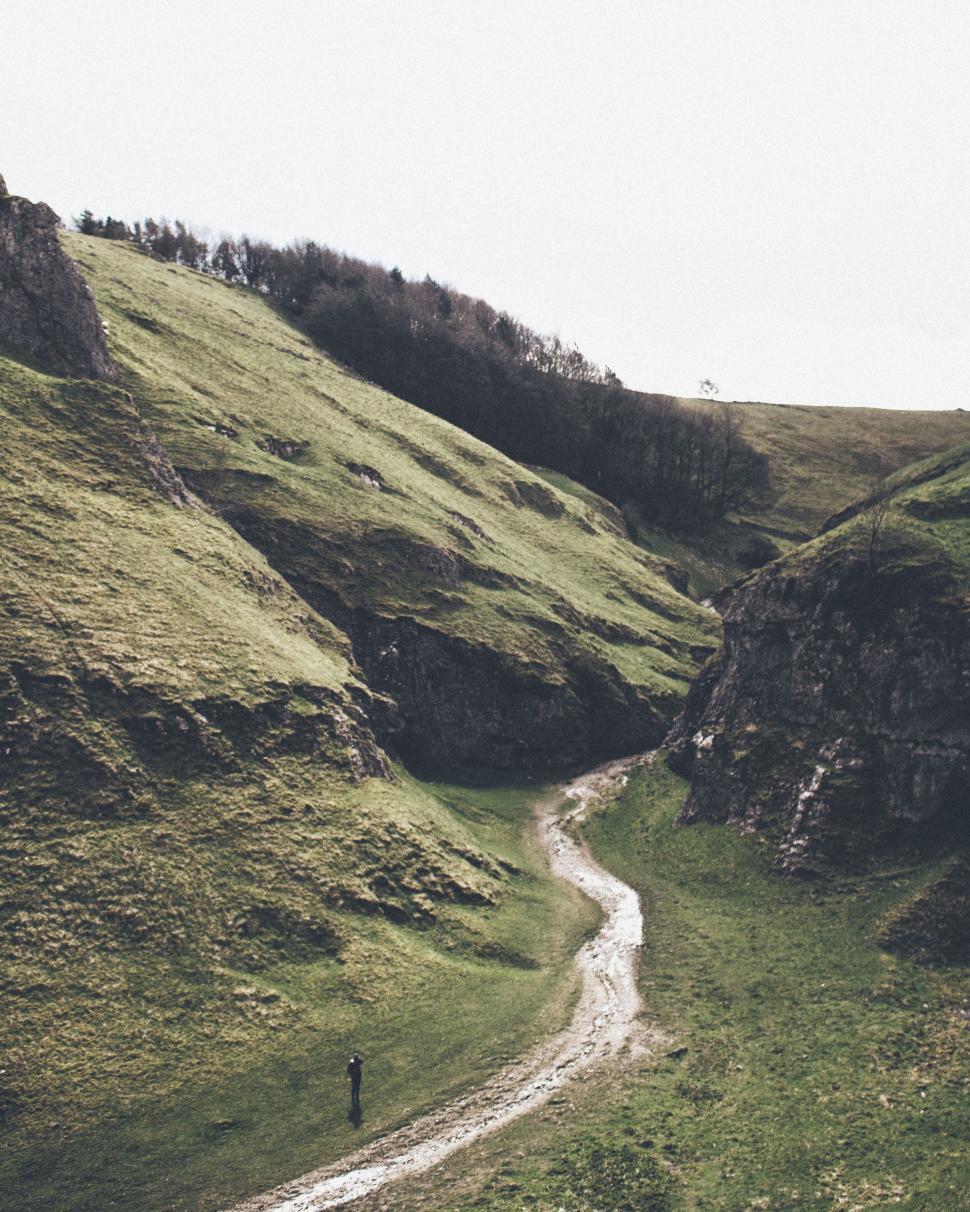 Free Image of Person Walking Down Dirt Road in Valley 