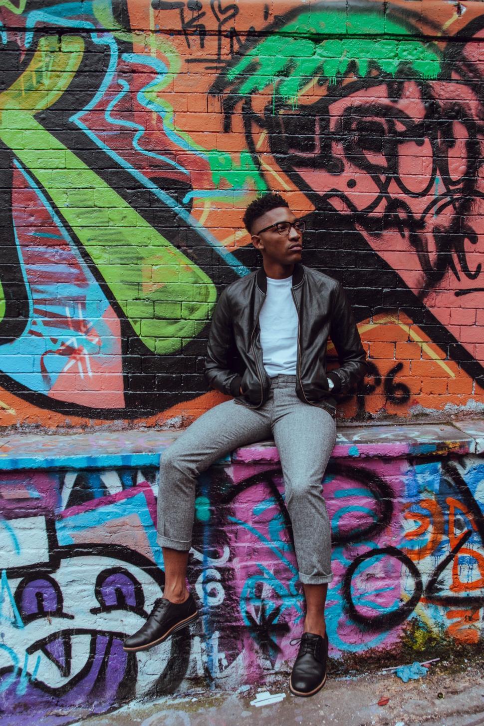 Free Image of Man Sitting on Graffiti-Covered Wall 