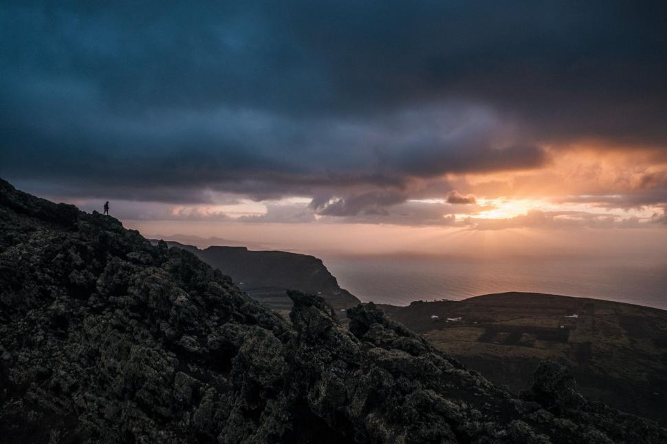 Free Image of Person Standing on Mountain Peak Under Cloudy Sky 