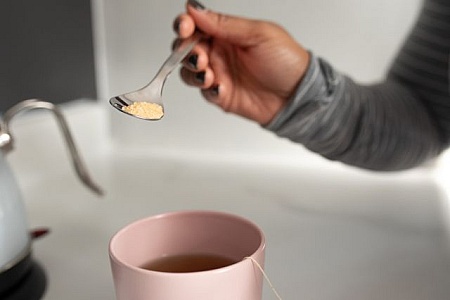 Crop view of female holding porcelain teapot and pouring hot tea into red  ceramic polka-dotted?