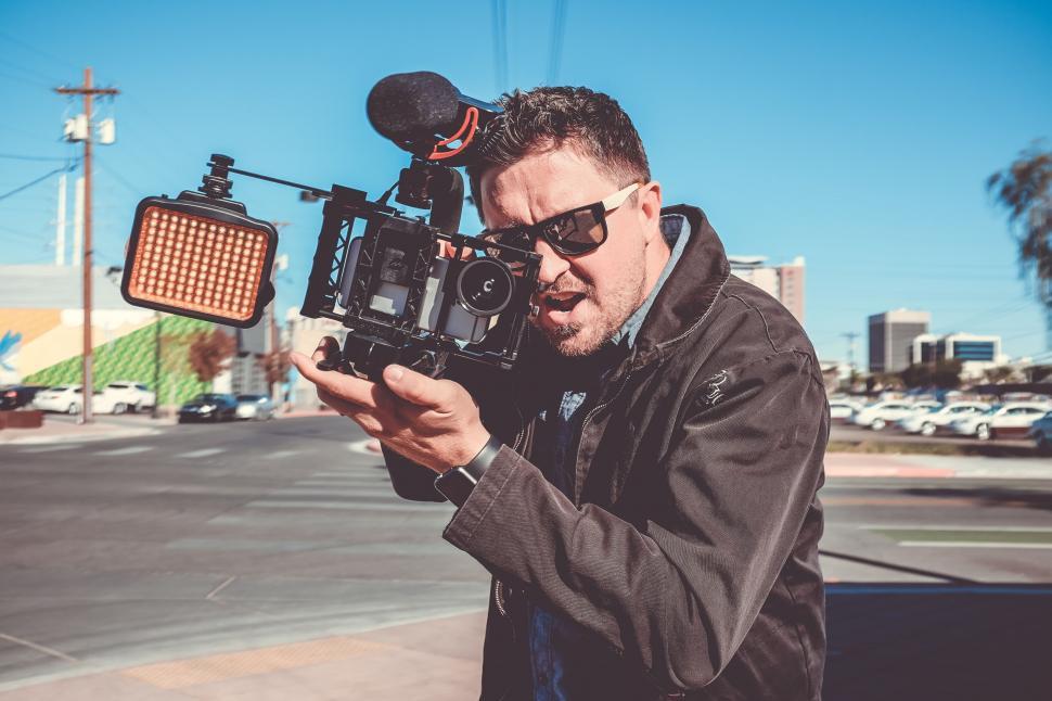 Free Image of Man Holding Camera in Front of Car 
