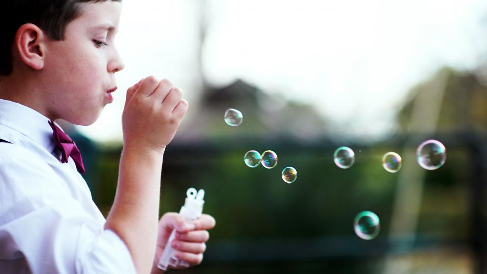 Free Image of Young Boy Blowing Bubbles in the Air 