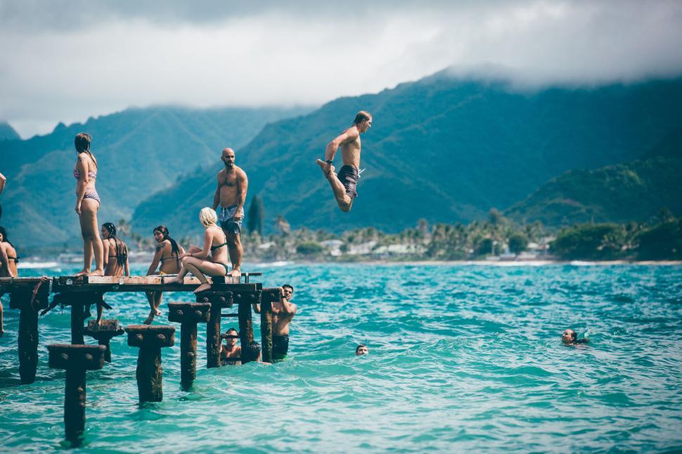 Free Image of Group of People Jumping Off Pier Into Water 
