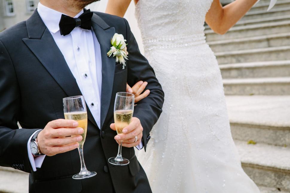 Free Image of Man in Tuxedo Holding Two Champagne Flutes 