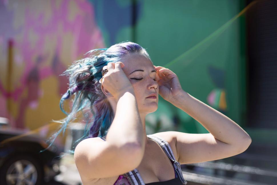 Free Image of Woman With Blue Hair Holding Her Head 