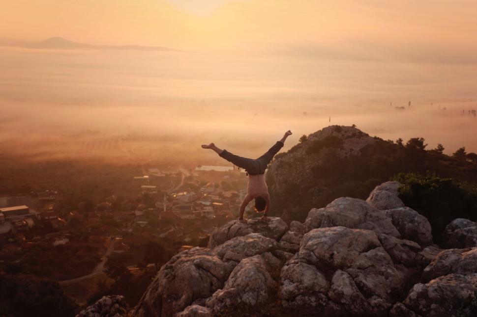 Free Image of Person Standing on Top of a Mountain With Arms Raised 