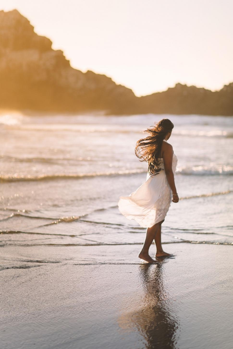 Free Image of Woman in White Dress Walking on Beach 
