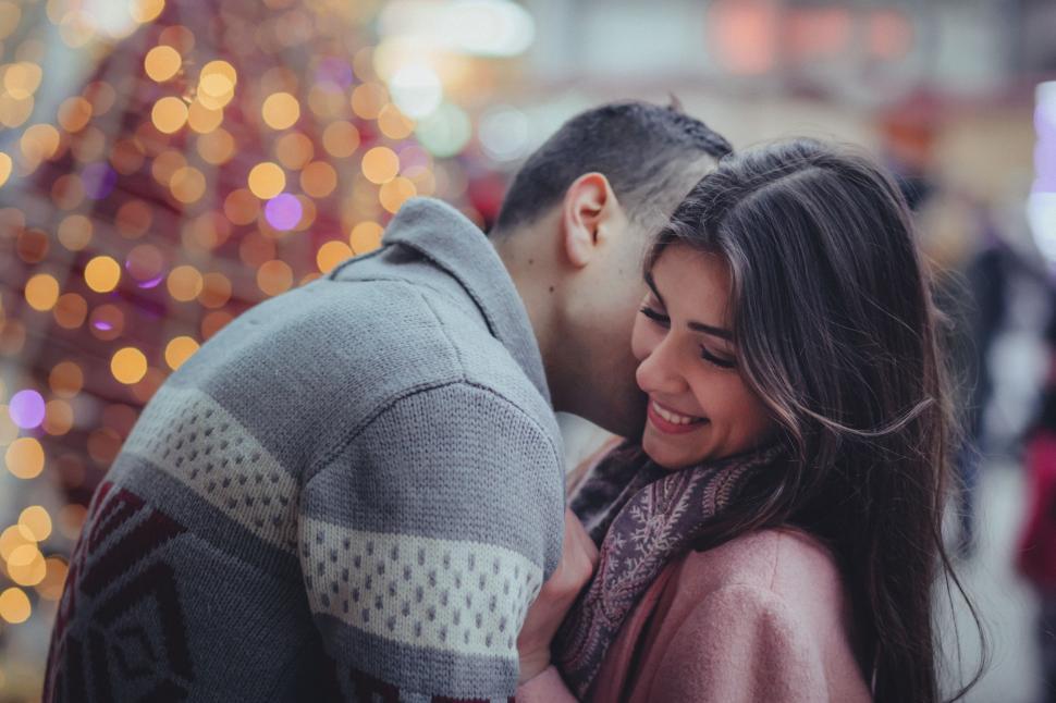 Free Image of Man and Woman Hugging in Front of Christmas Tree 