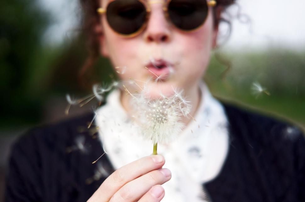Free Image of Woman Wearing Sunglasses Blowing a Dandelion 