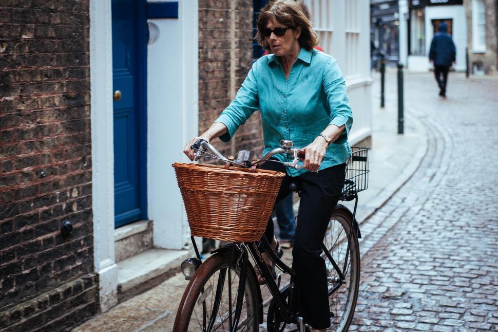 Free Image of Woman Riding Bike Down Cobblestone Street 