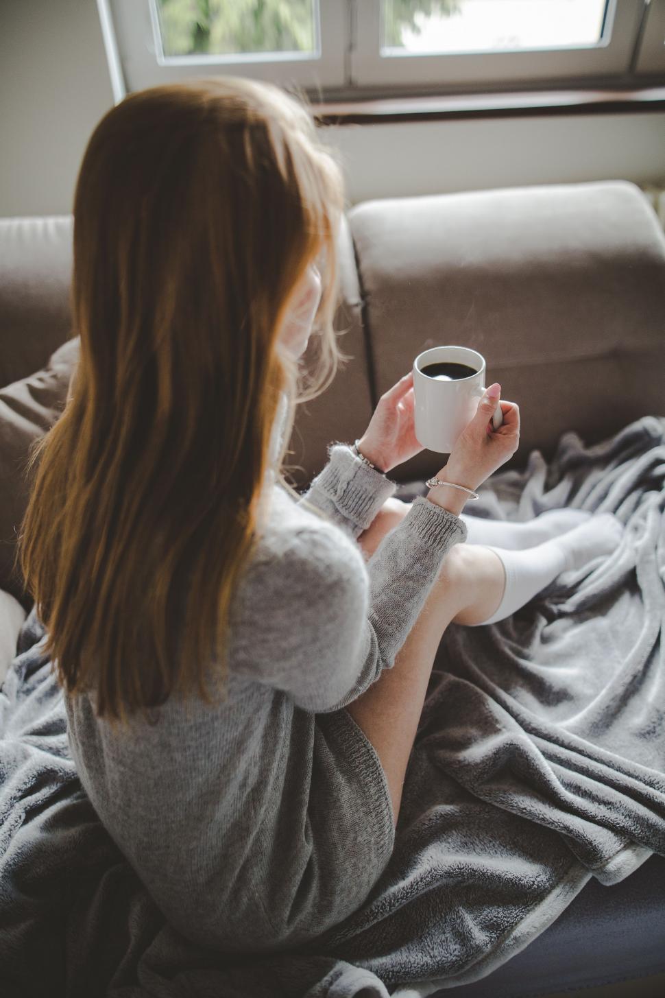 Free Image of Woman Sitting on Couch Holding Cup of Coffee 