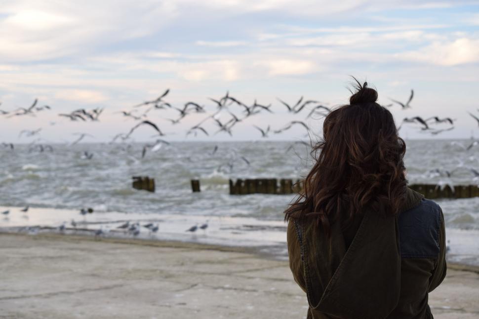 Free Image of Woman Standing in Front of a Flock of Birds 