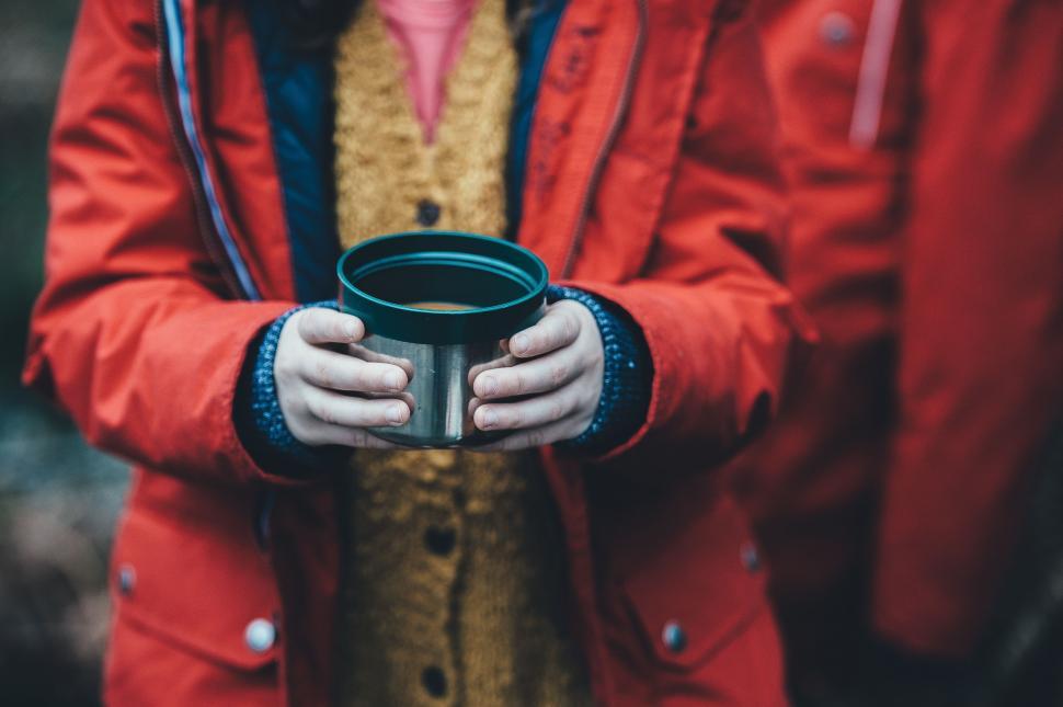 Free Image of Person in Red Jacket Holding Cup 