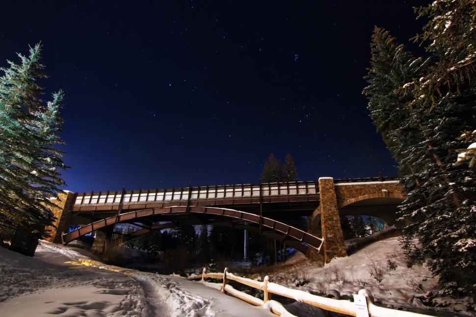 Free Image of Bridge Over Snow Covered River at Night 