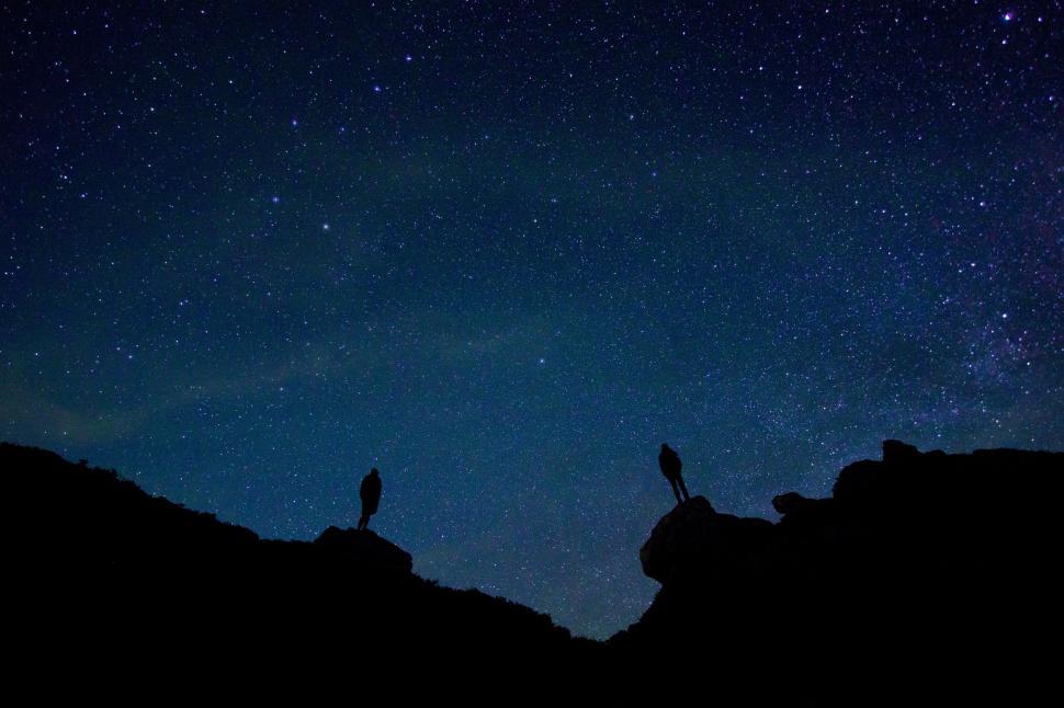 Free Image of Two Birds Standing on Top of a Mountain Under a Night Sky 