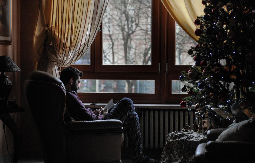 Free Image of Man Sitting in Chair in Front of Christmas Tree 
