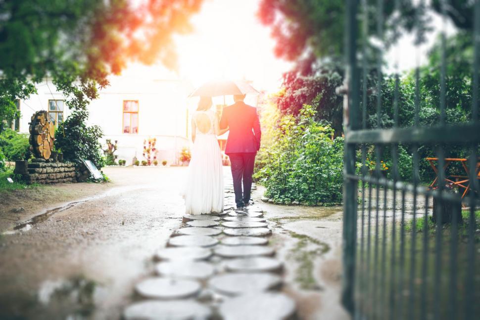 Free Image of Bride and Groom Walking Down Path Under Umbrella 