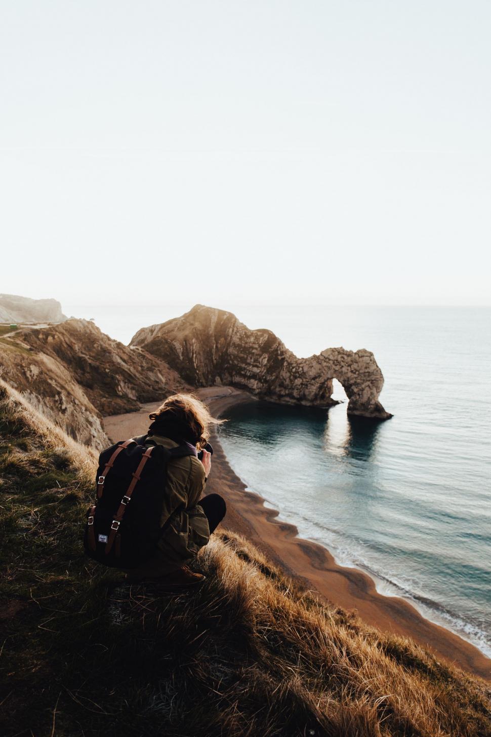 Free Image of Person Sitting on Cliff Overlooking Ocean 