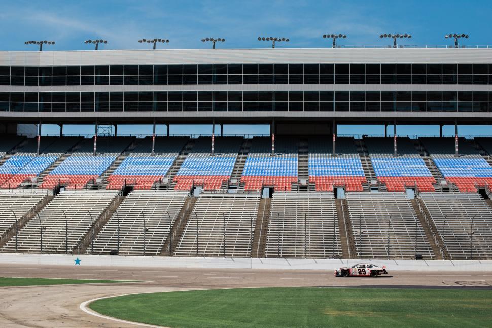 Free Image of Race Car Speeding Down Track in Front of Empty Stadium 