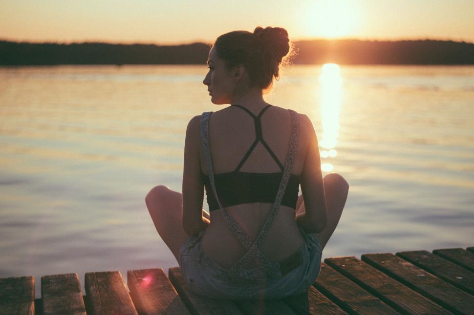 Free Image of Woman Sitting on Dock Looking at Water 