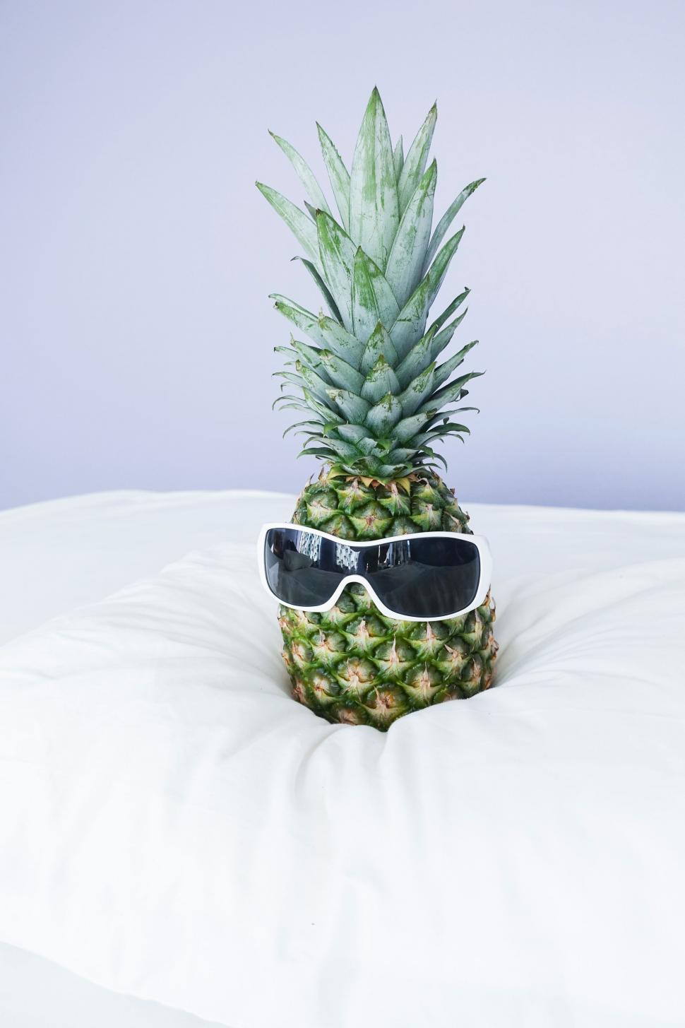 Free Image of Pineapple Wearing Sunglasses on Bed 