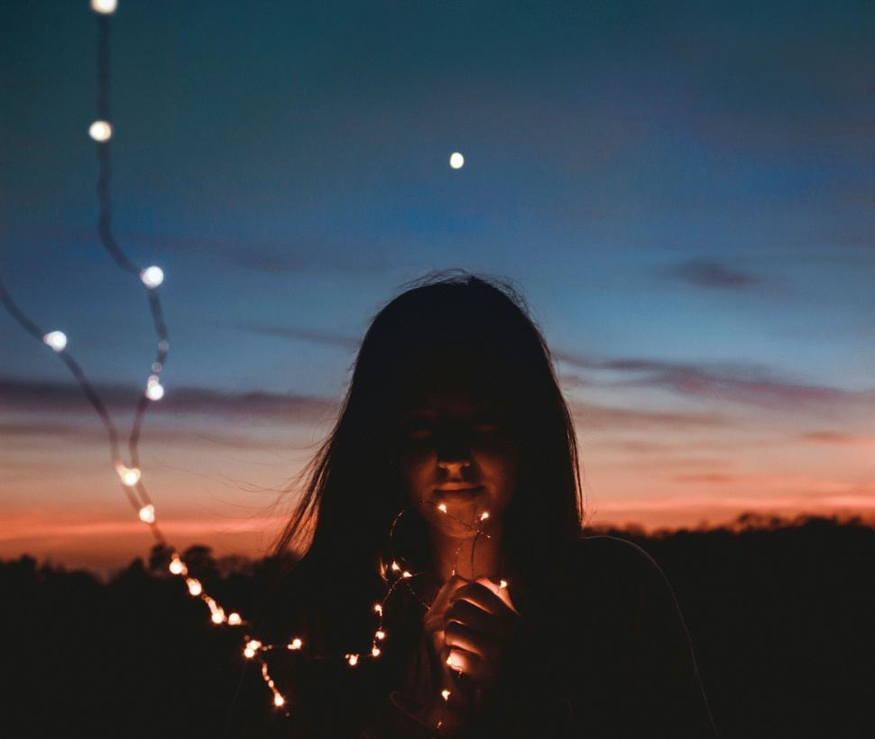 Free Image of Woman Holding String of Lights in Front of Face 