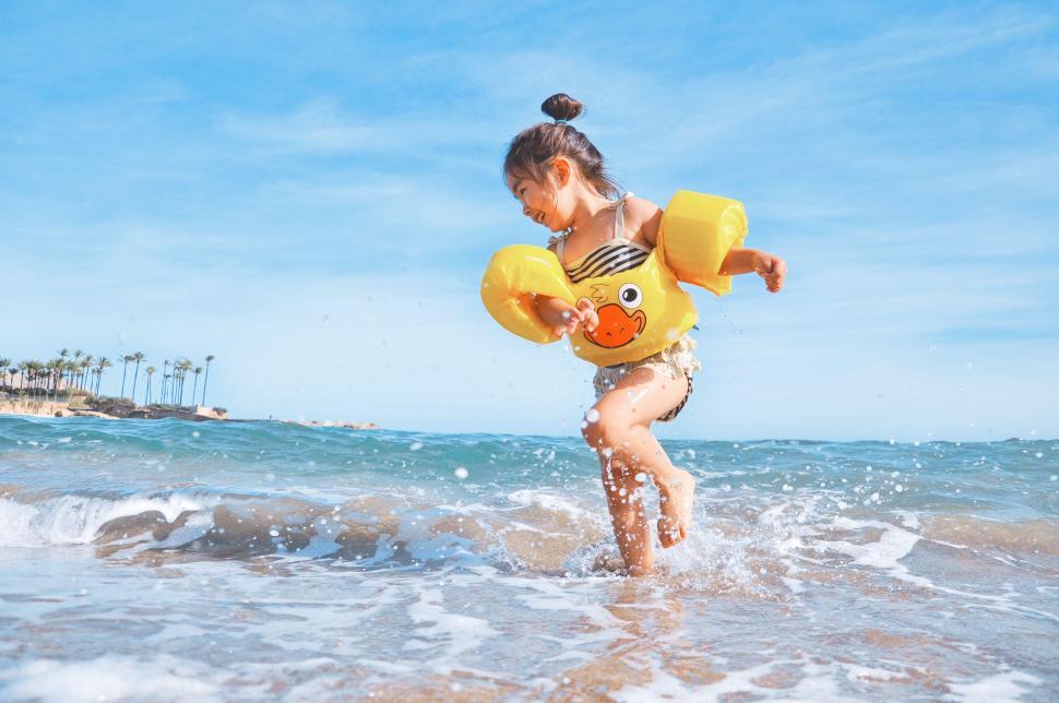 Free Image of Little Girl Playing in the Ocean With Inflatable Rubber Duck 