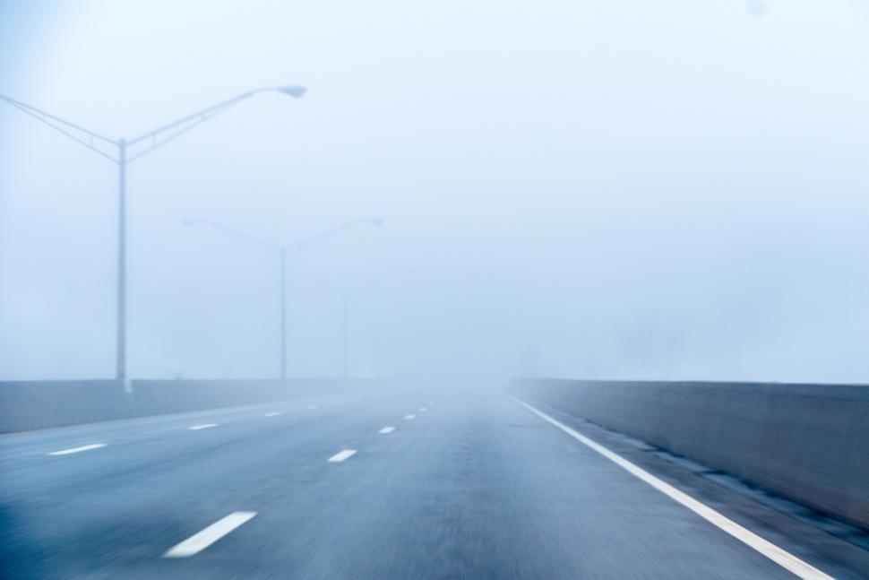 Free Image of A Car Driving on a Foggy Road in the Middle of the Day 