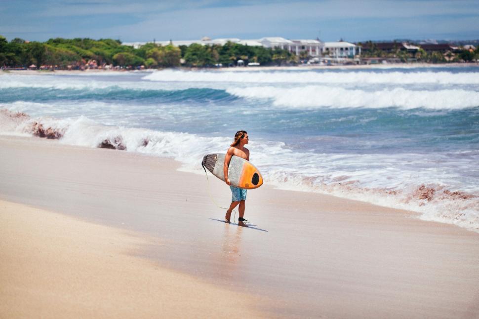 Free Image of Man Holding Surfboard on Sandy Beach 
