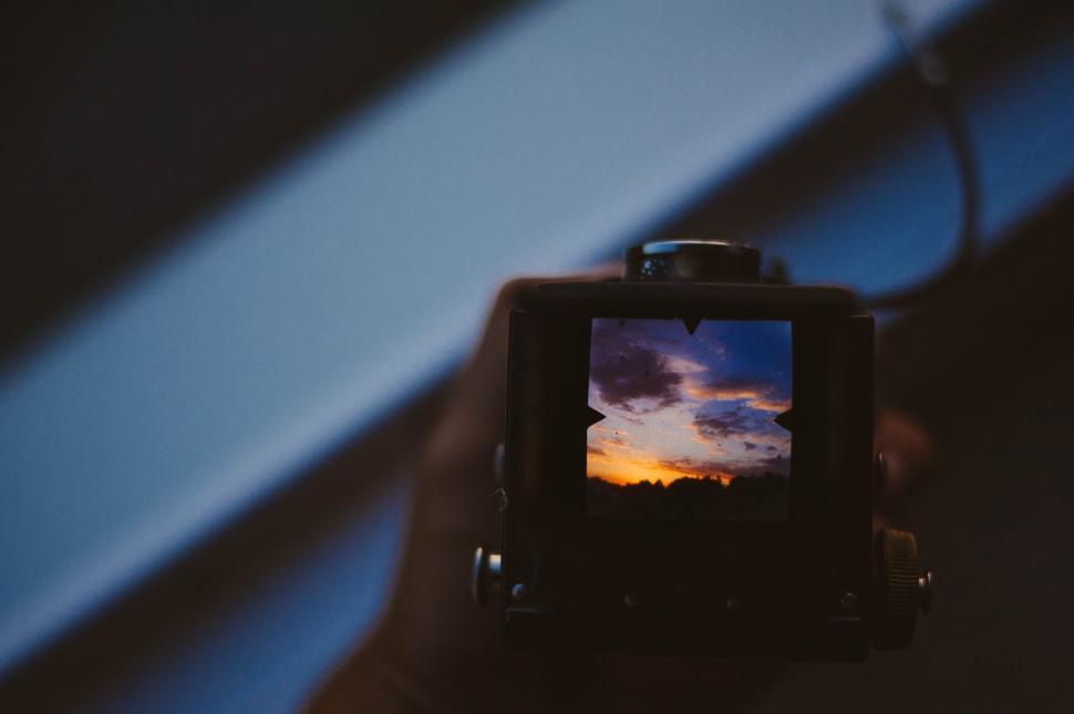 Free Image of Person Holding Camera With Sunset Background 